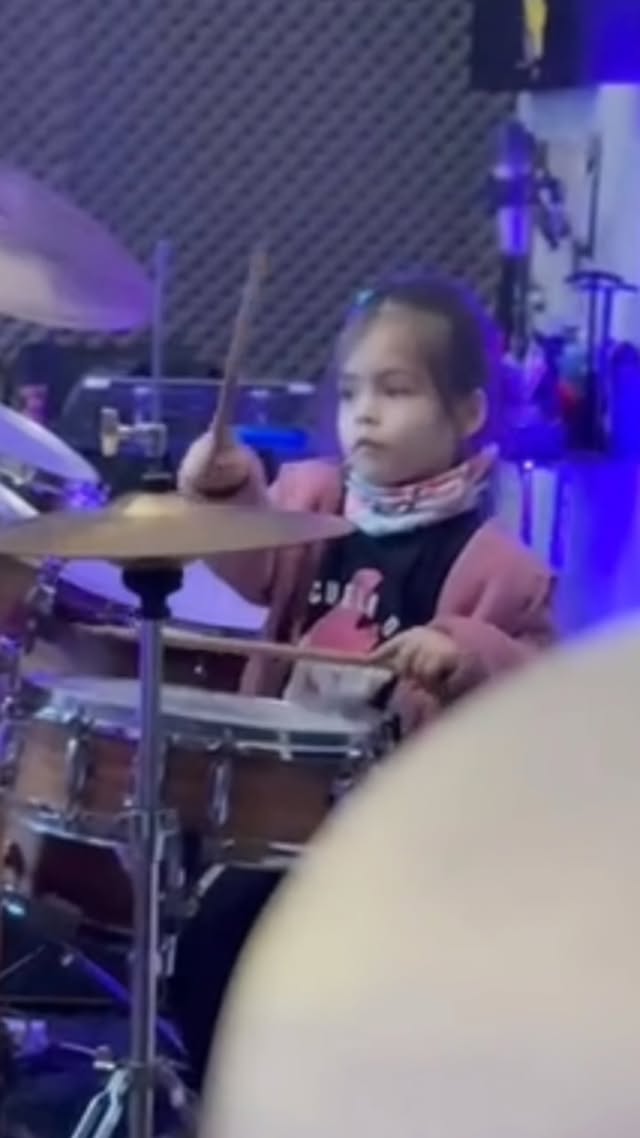 Alumna tocando batería en la escuela